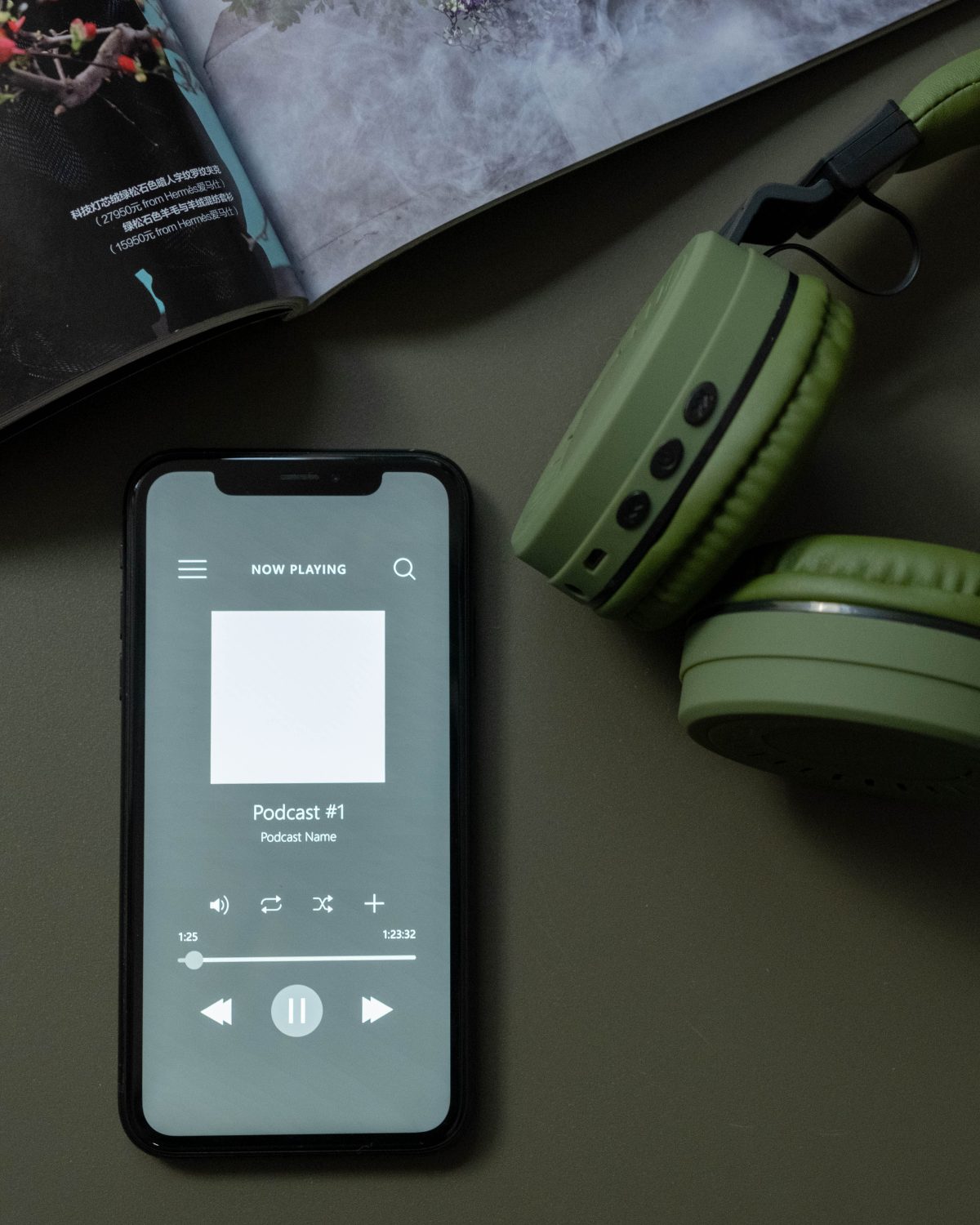 Podcast episode playing in a phone app next to a pair of headphones