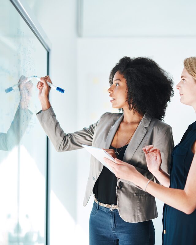Marketing team mapping out a podcast launch package on a glass board